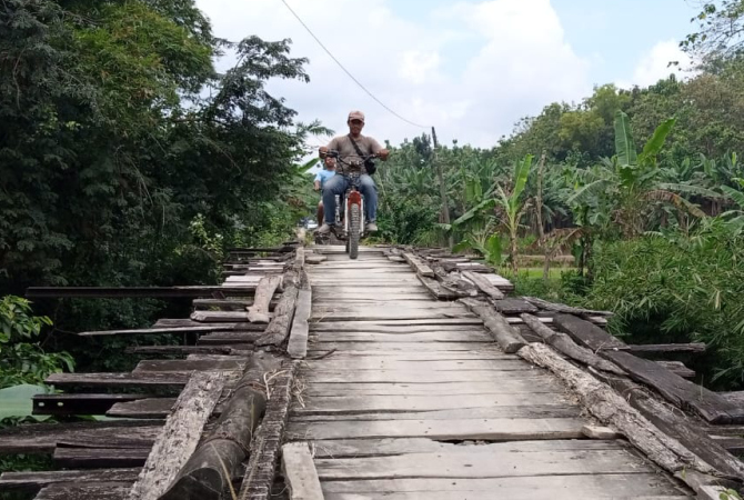 MELINTAS: Salah seorang warga melintasi jembatan rusak di Grobogan baru-baru ini. (EKO SANTOSO/RADAR KUDUS)