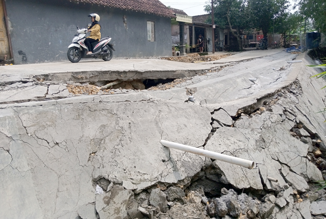 PARAH: Warga saat melintas di jalan rusak yang berada di Dusun Gempolpayung, Kelurahan Purwodadi, Kamis (8/12). (EKO SANTOSO/RADAR KUDUS)