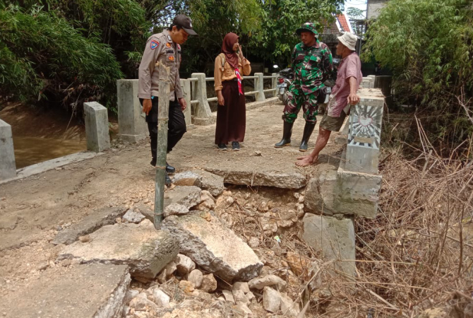 CEK LOKASI : Anggota Polsek Grobogan mengecek jembatan longsor di Desa Putatsari, Kecamatan Grobogan dan memasang rambu agar warga memutar tidak melewati jembatan. (SIROJUL MUNIR/RADAR KUDUS)