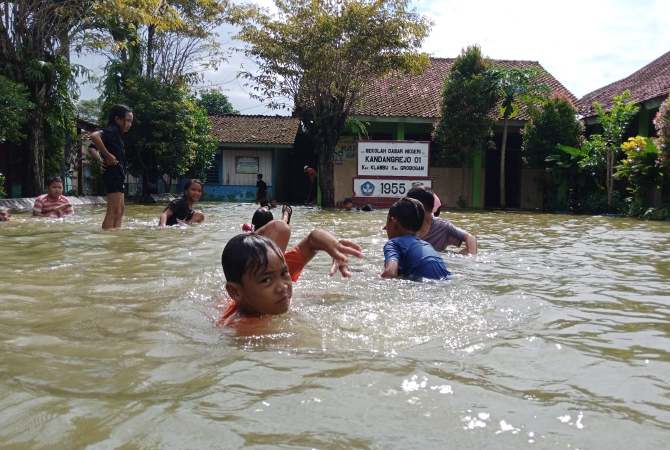 BERMAIN: Siswa SDN 1 Kandangrejo berenang di halaman sekolah pada Selasa (10/1). (EKO SANTOSO/RADAR KUDUS)