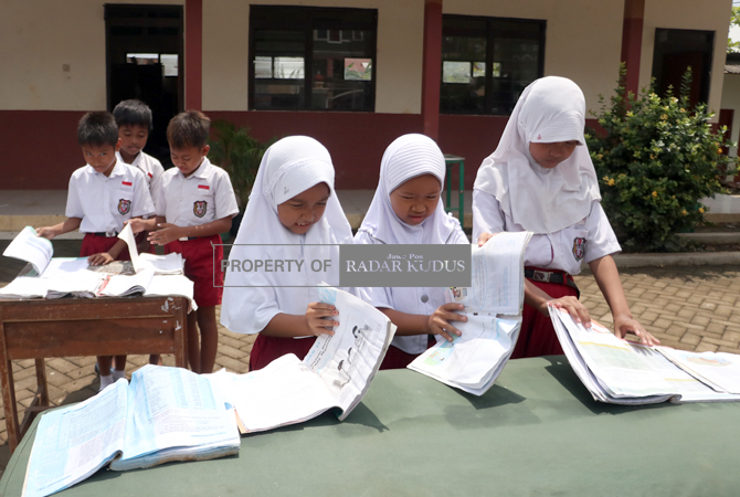 BERSIH-BERSIH: Para siswa SD 03 Jati Wetan, Jati, Kudus, menjemur buku pelajaran kemarin. Sekolah itu terendam banjir hampir dua pekan. (DONNY SETYAWAN/RADAR KUDUS)