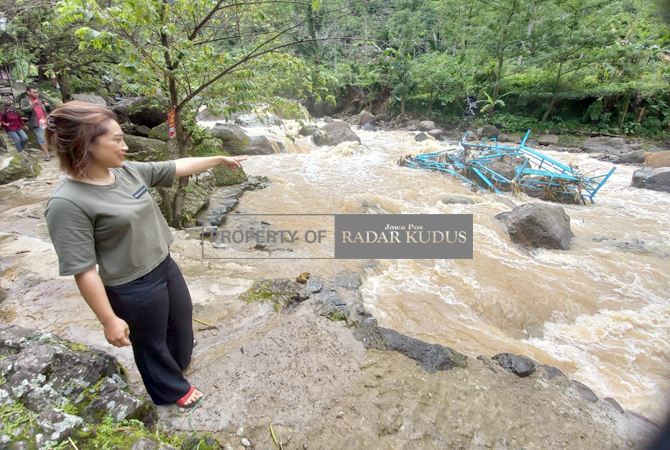 TINGGAL SISA: Ngatri, pemilik rumah makan dan tempat wisata di Desa Rahtawu, Gebog, Kudus, menunjukkan lokasi semula jembatan dan sejumlah gazebo yang terbawa derasnya arus sungai, Kamis (26/1). (DONNY SETYAWAN/RADAR KUDUS)