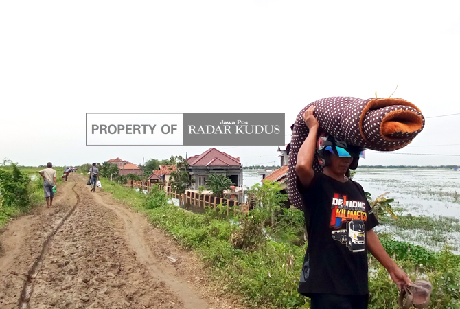 JALAN DUA KILOMETER: Warga Dukuh Goleng, Pasuruhan Lor, Kecamatan Jati, Kudus, saat pulang mengambil barang dari rumah kemarin. (ARIKA KHOIRIYA/RADAR KUDUS)