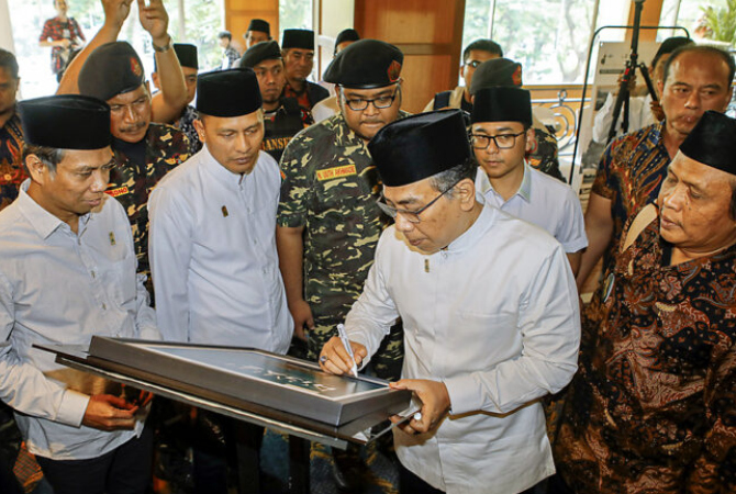 SAKSI SEJARAH: Ketua Umum PBNU KH Yahya Cholil Staquf menandatangani salah satu poster yang dipamerkan dalam acara Muktamar Internasional Fikih Peradaban di Hotel Shanri-La, Surabaya, kemarin (5/2). (DIPTA WAHYU/JAWA POS)