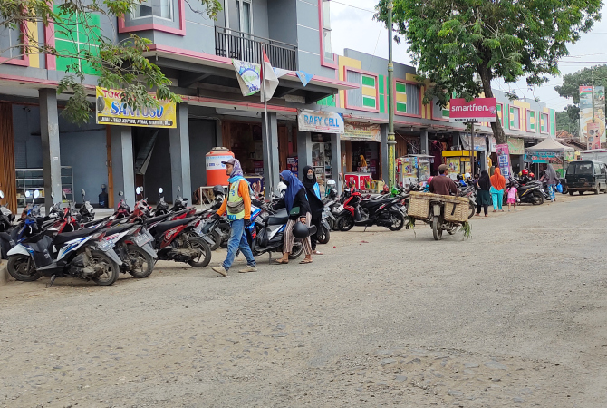 ATUR MOTOR: Seorang juru parkir di depan Pasar Ngawen tampak membantu pengunjung menata motornya pada Selasa (31/1). (AHMAD ZA’IIMUL CHANIEF/RADAR KUDUS)