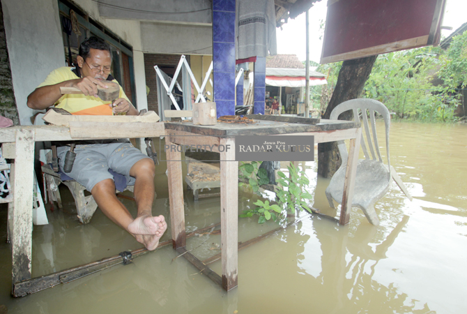SANTAI: Warga Desa Tegalsambi tetap mengukir meski rumahnya terendam banjir, Minggu (26/2). (MOH. NUR SYAHRI MUHARROM/RADAR KUDUS)