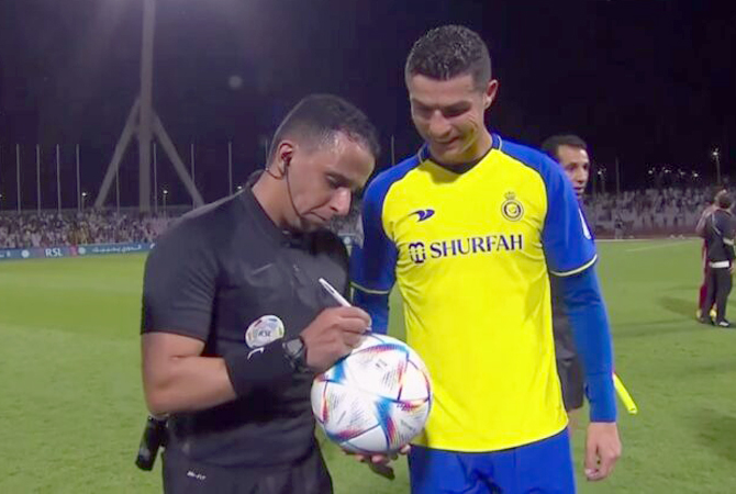 Cristiano Ronaldo berpose dengan wasit Sultan Al Harbi dan bola yang ditandatangani pengadil lapangan tersebut seusai laga Saudi Pro League antara Al Wehda versus Al Nassr (10/2) WIB. (ROSHN SAUDI LEAGUE VIA YOUTUBE )