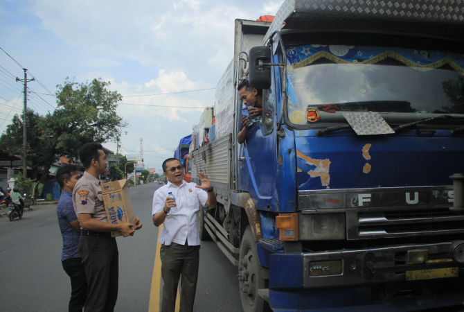 IKUT PEDULI: Kepala Kejaksaan Negeri Rembang, Muhamat Fahrorozi bersama jajarannya membagiakan air minum kepada sopir truk saat terjebak kemacetan, Rabu (3/1). (WISNU AJI/RADAR KUDUS)