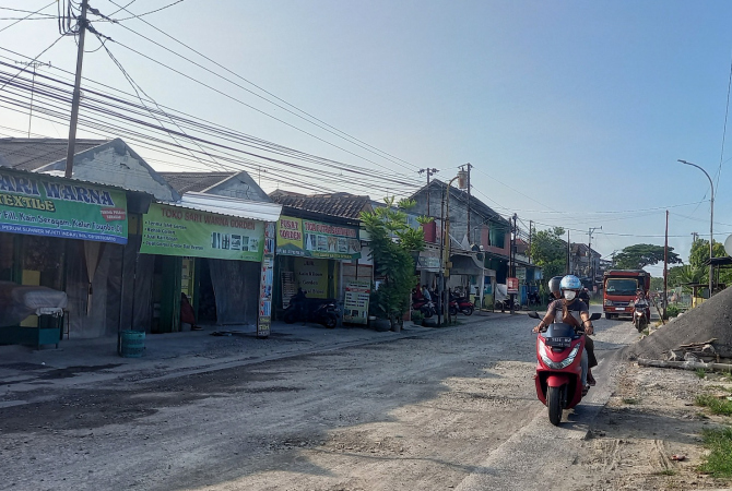 REMUK: Pengendara melewati Jalan Selamet Riyadi yang remuk setelah tak diteruskan pekerjaannya olah kontraktor. (VACHRI RINALDY L/RADAR KUDUS)