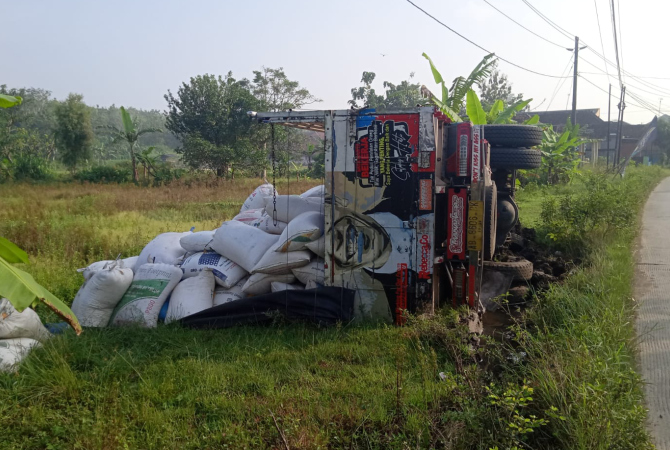 TERGULING: Truk bermuatan 10 ton jagung bernomor polisi AB 8606 BK terguling di Jalan Raya Karangrayung-Juwangi, Jumat (17/3). (NOER FOR RADAR KUDUS)