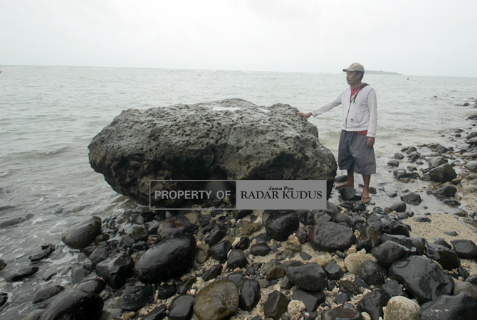 MUJARAB: Warga komplek Pantai Kartini melihat batu karang yang dinamai Karanggenuk. Mandi di sekitar batu tersebut dipercaya manjur mengobati berbagai penyakit. (MOH. NUR SYAHRI MUHARROM/RADAR KUDUS)