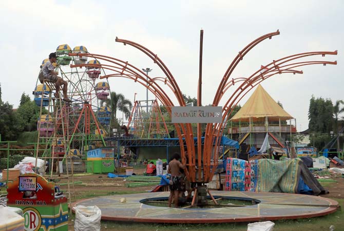 BONGKAR: Terlihat pedagang membongkar permainan di Alun-alun Simpang Tujuh setelah dandangan selesai kemarin. (DONNY SETYAWAN/RADAR KUDUS)