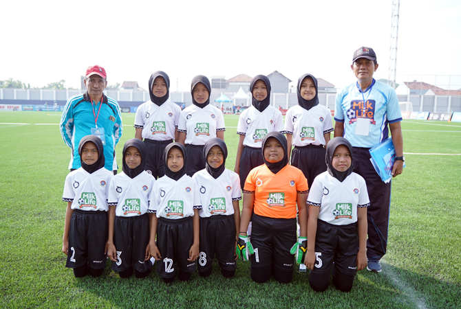 Kepala SD 2 Adiwarno, Kamsun (paling kiri topi merah) mendampingi para siswi untuk berlaga dalam turnamen MilkLife Soccer Challenge 2023 yang diselenggarakan di Supersoccer Arena, Rendeng. Sebagai bentuk dukungan, ia dan para guru rela menjadikan kendaraa
