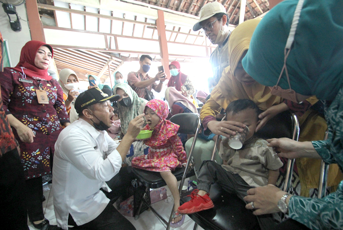 KERJA CEPAT: PJ Bupati Jepara Edy Supriyanta menyuapkan makanan bergizi seimbang untuk salah satu bayi asal Desa Sowan Lor, Kedung, belum lama ini. (MOH. NUR SYAHRI MUHARROM/RADAR KUDUS)