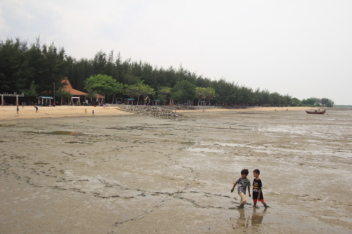 TERJEBAK LUMPUR: Anak-anak mencari ikan meski terjebak lumpur saat air laut surut di pantai Wates Kaliori. (WISNU AJI/RADAR KUDUS)