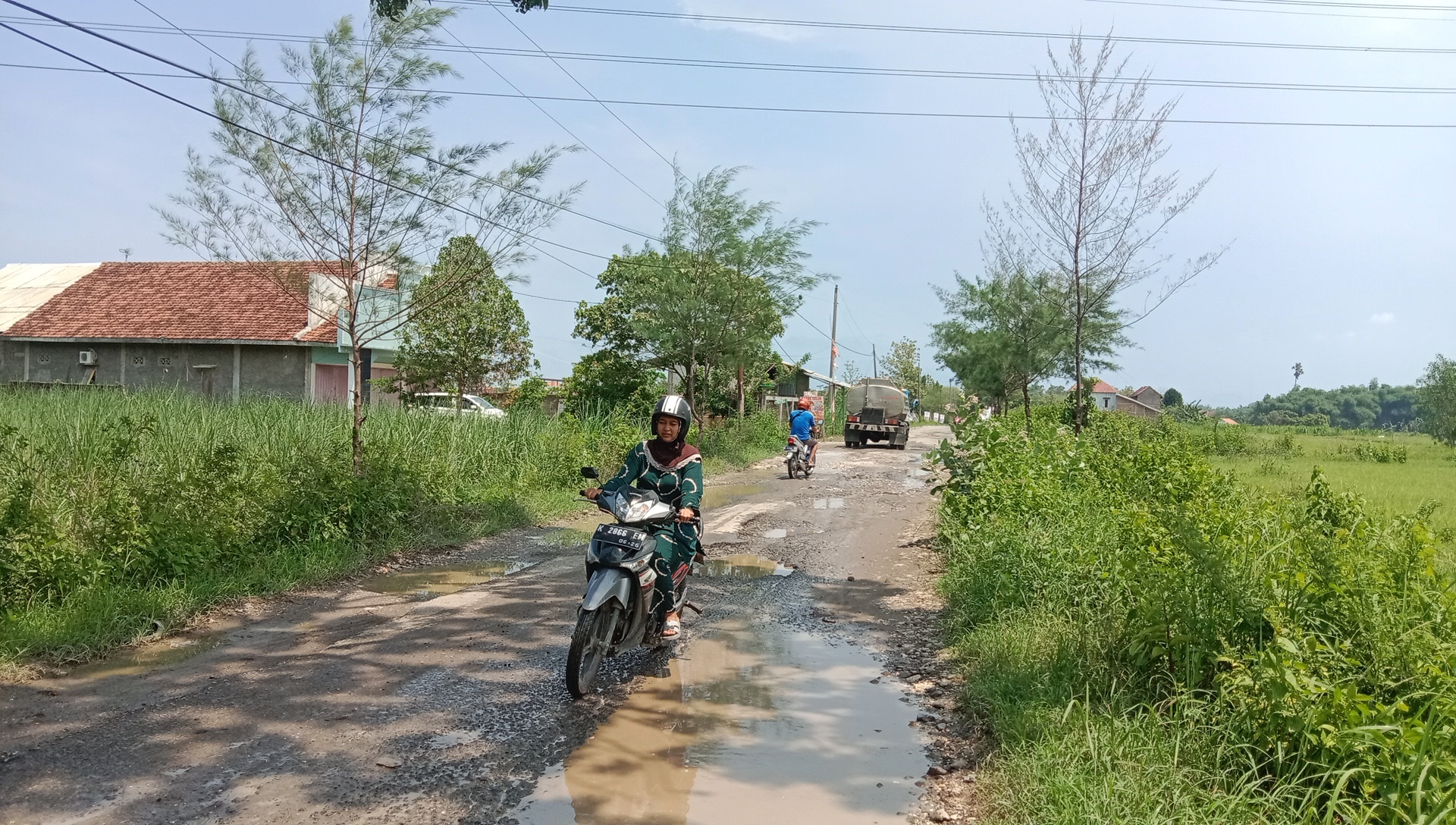 BECEK: Pengendara melintas di Jalan Turusgede yang becek kemarin. (VACHRI RINALDY L/RADAR KUDUS)