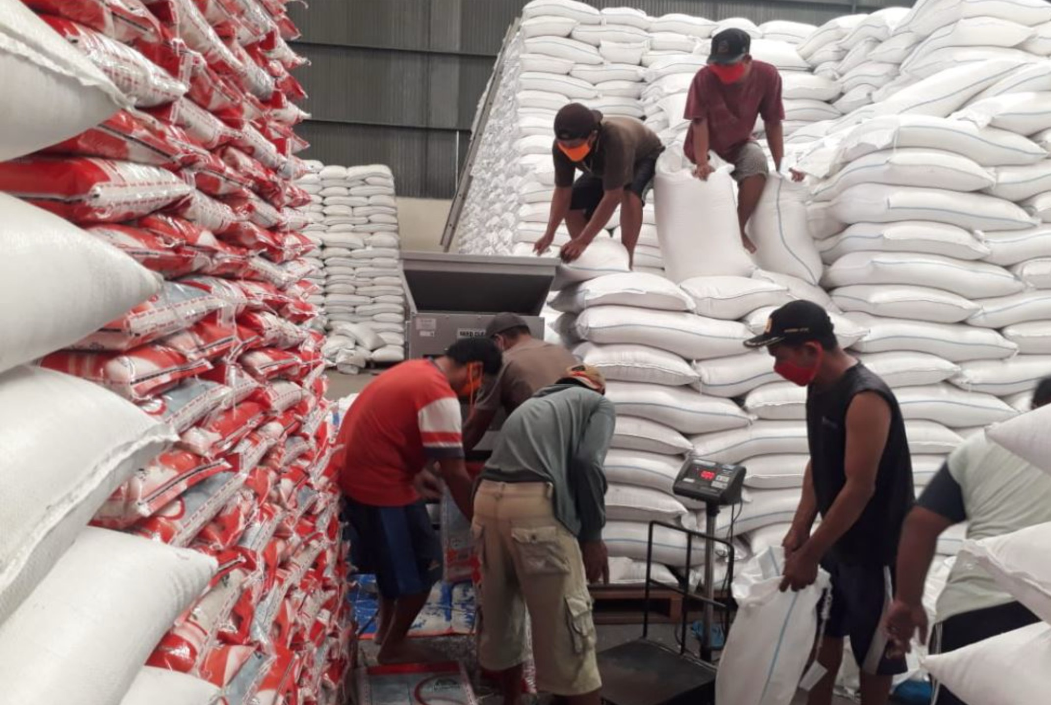 BANTUAN: Pekerja melakukan penimbangan beras untuk bansos sembako.