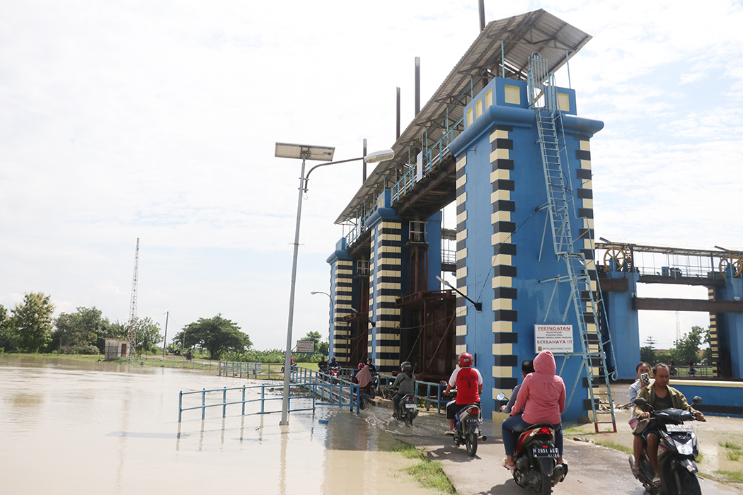 AIR PENUH: Sejumlah pengendara motor melewati jembatan pintu air Bendung Wilalung yang sudah tergenang air kemarin.