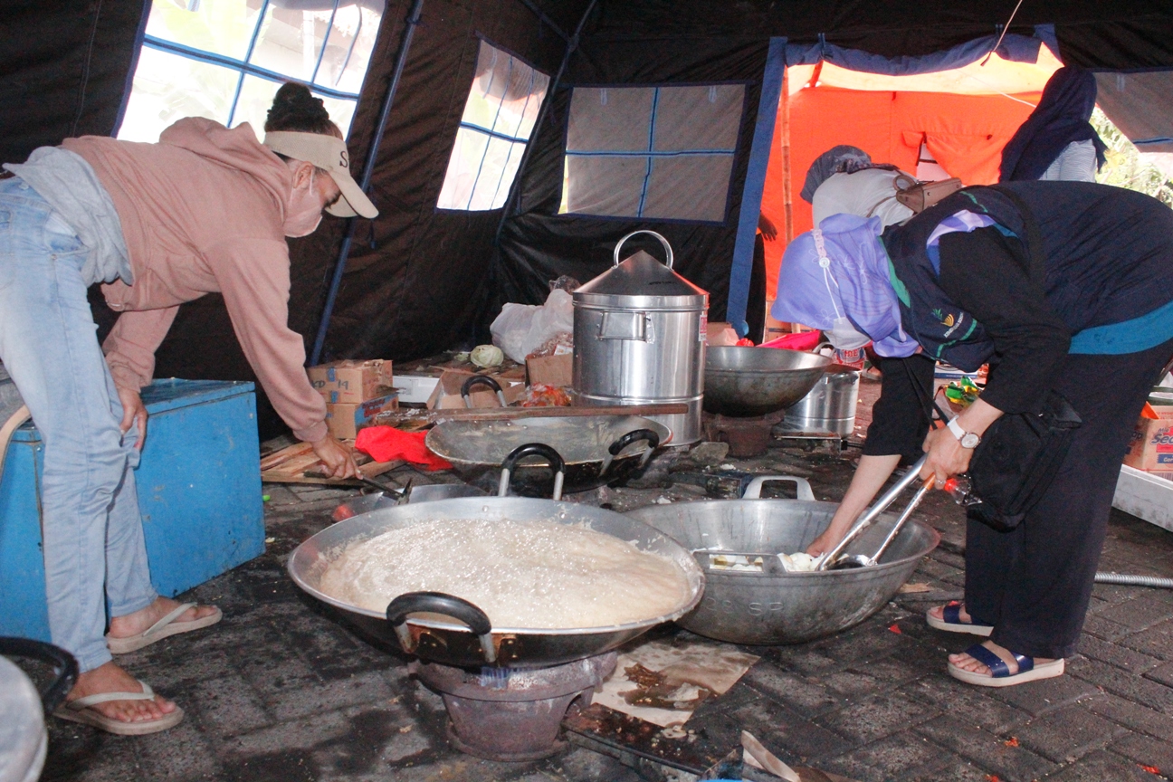 MEMASAK : Warga dan petugas dapur umum saat memasak di lokasi pengungsian Terminal Jati Kudus kemarin pagi.