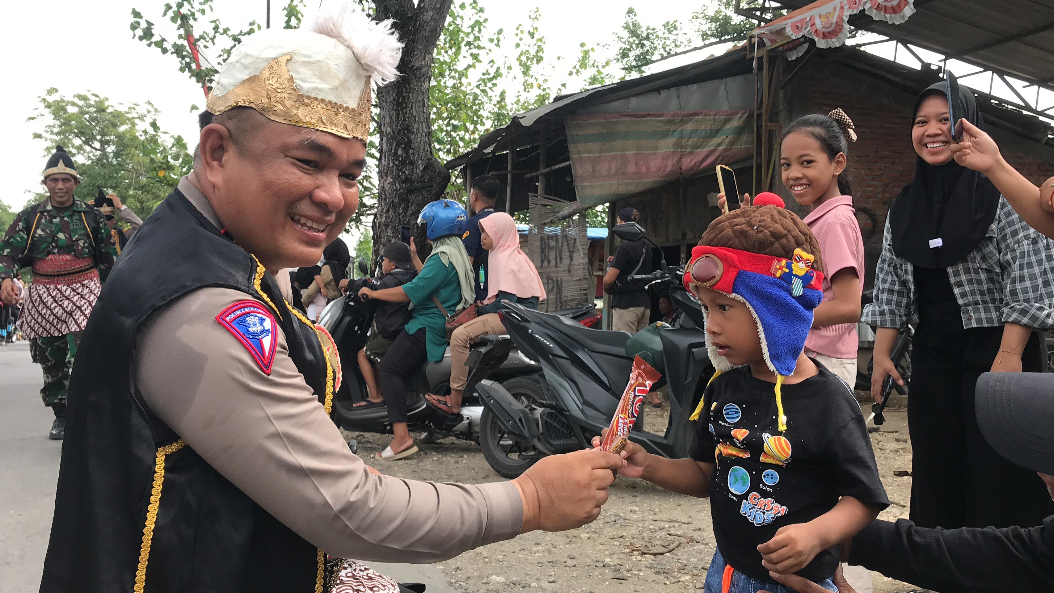 PEDULI: Kasat Lantas Polres Grobogan AKP Tejo Suwono mengenakan kostum pewayangan membagikan cokelat dan permen kepada warga yang menonton.