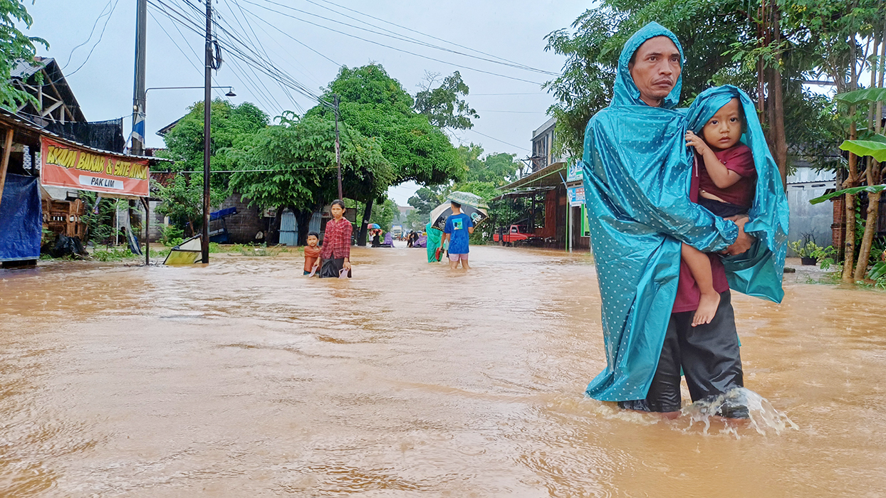 MENONTON: Seorang warga dari Sowan Lor, Kecamatan Kedung, Jepara, membopong anaknya melihat keramaian akibat banjir.
