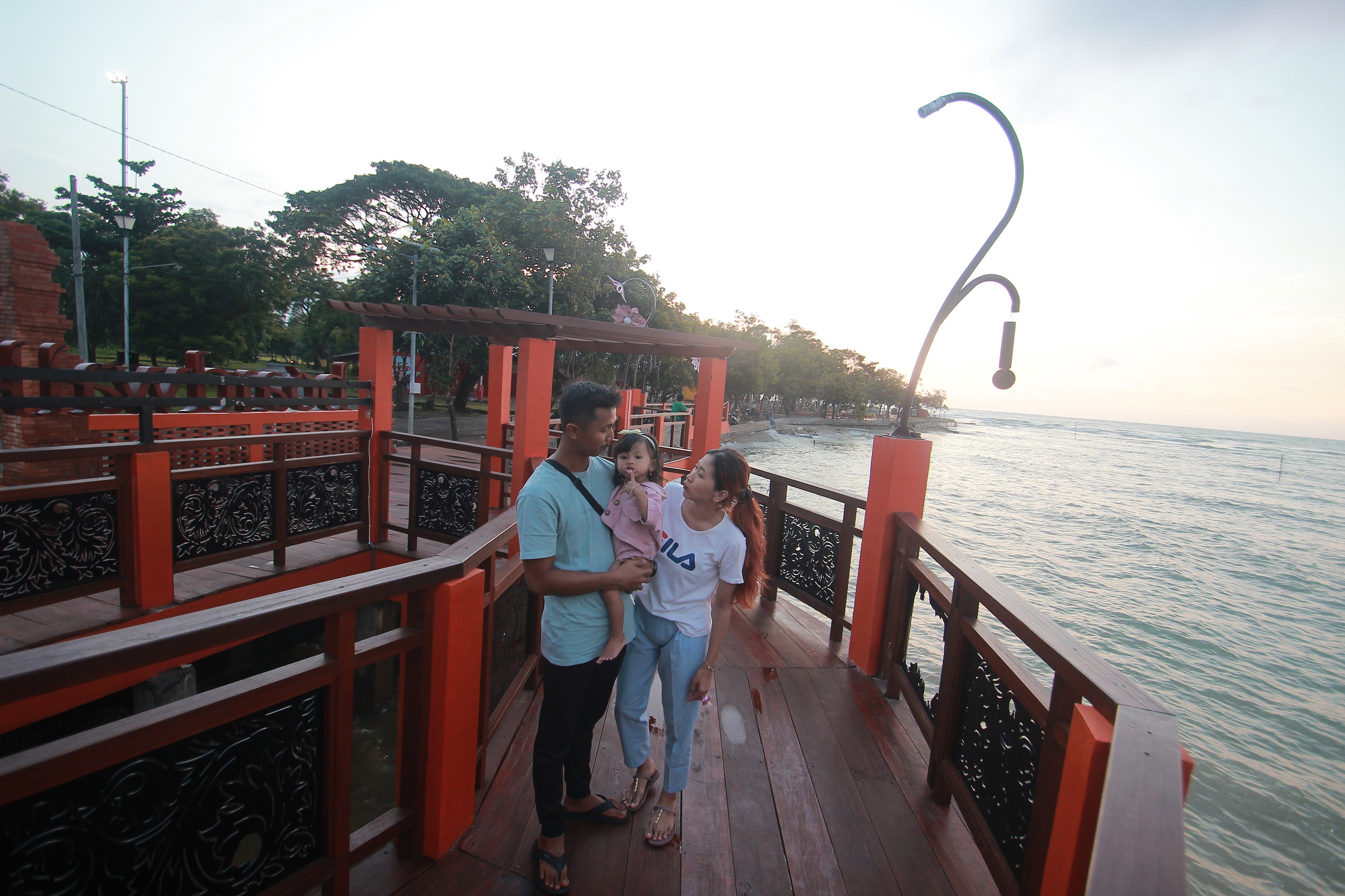DIKEMBANGKAN: Sebuah keluarga menghabiskan waktu sore di area dermaga boardwalk Pantai Bandengan, tahun ini tempat serupa akan dikembangkan lagi. (MOH. NUR SYAHRI MUHARROM/RADAR KUDUS)