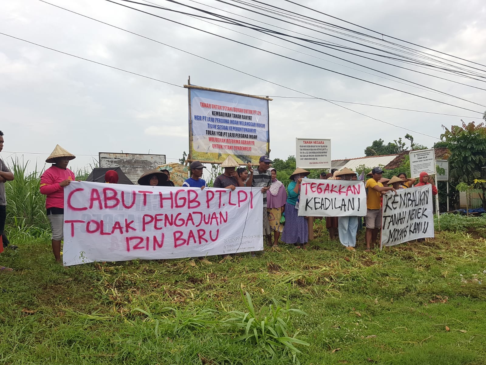 GELAR POSTER: Warga Desa Pundenrejo, Tayu, menggelar poster memprotes dugaan penyerobotan lahan oleh perusahaan belum lama ini. (ANDRE FAIDHIL FALAH/RADAR KUDUS)