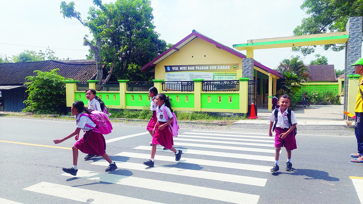 BAHAGIA: Siswa-siswi SDN Cabak Cepu menyebrang jalan raya setelah pulang sekolah, kemaren. (ARIF FAKHRIAN KHALIM/RADARPATI.ID)