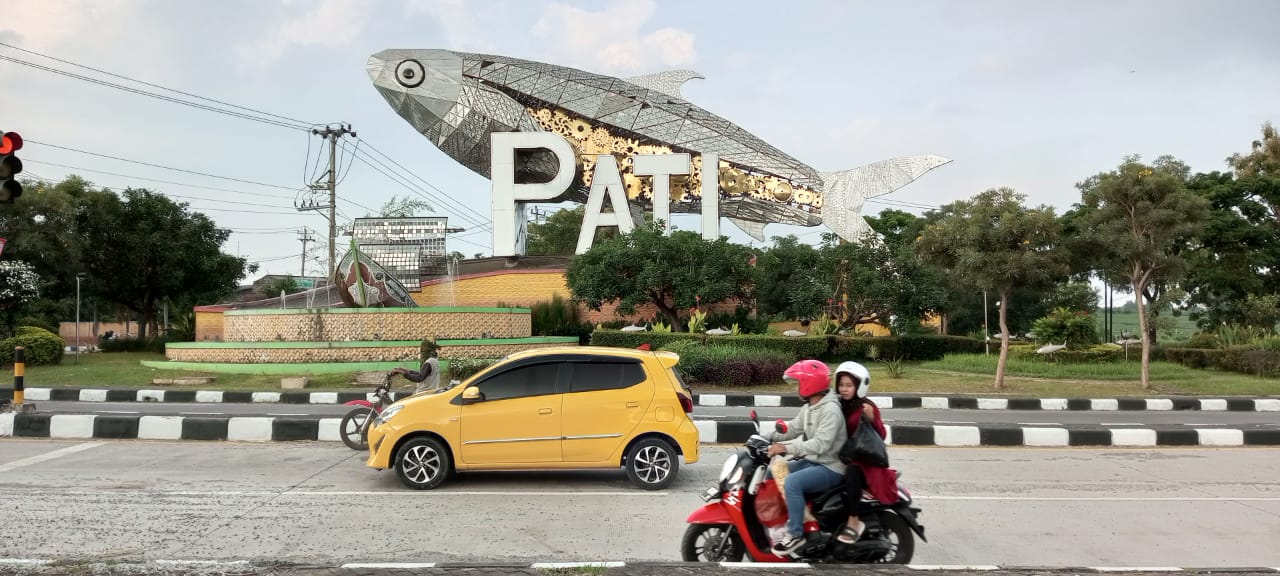 IKON : Pengendara melintas di jalanan dengan latar belakang patung bandeng raksasa di pertigaan jalan lingkar selatan. (ACHMAD ULIL ALBAB/RADAR KUDUS)