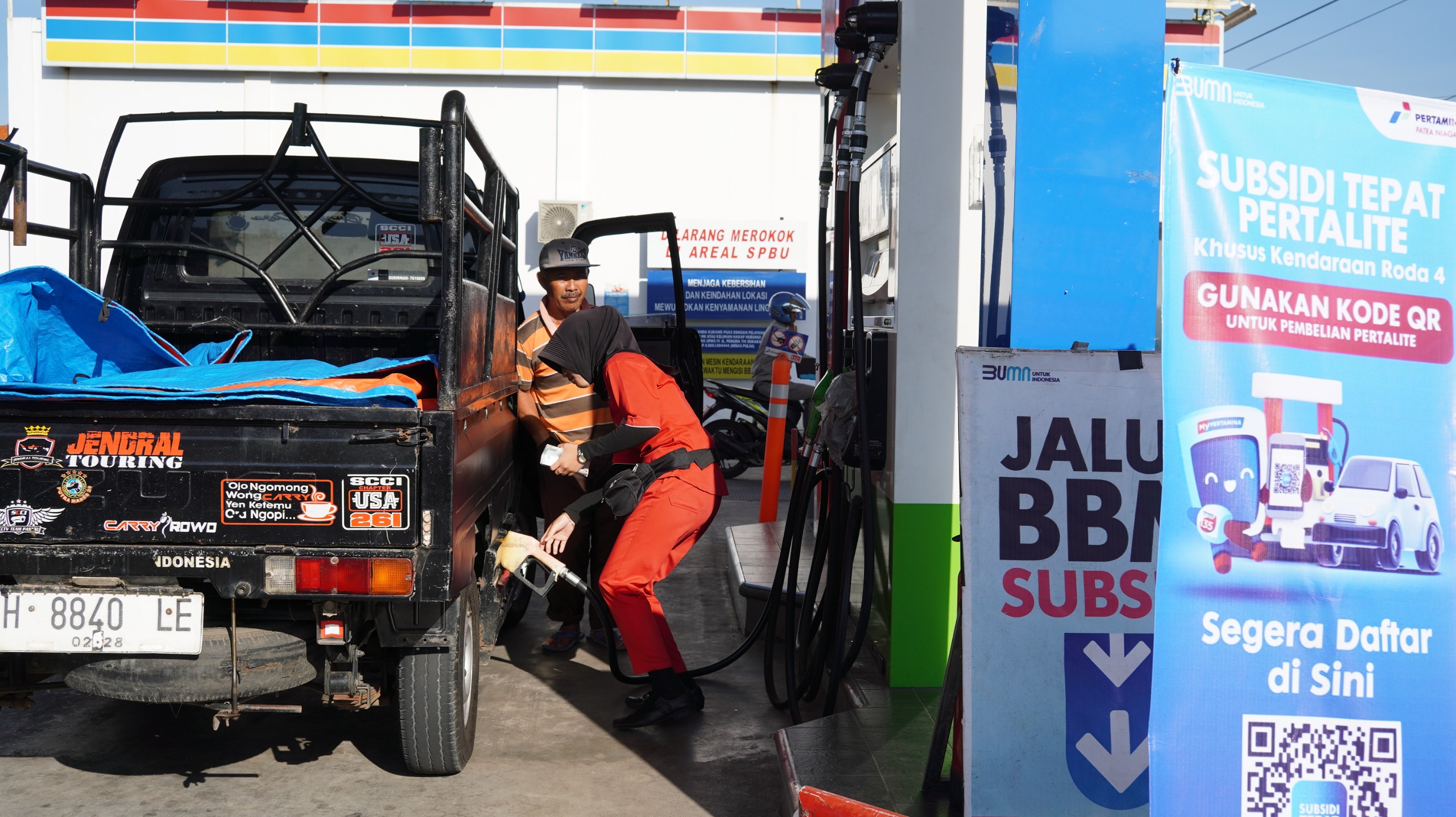 MELAYANI PEMBELI: Petugas SPBU saat melayani pembelian BBM. Terpasang banner Subsidi Tepat Pertalite