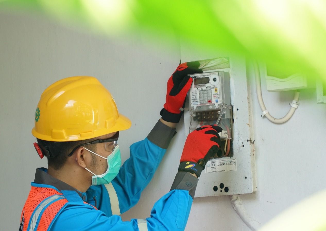 PERHATIAN : Petugas PLN sedang membenahi meteran listrik di salah satu rumah pelanggan. (PLN FOTO)