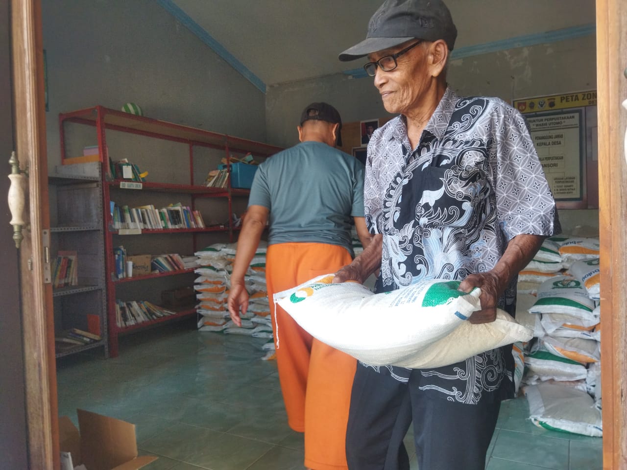 DIBANTU: Salah satu penerima bantuan mengambil beras di kantor balai Desa/Kecamatan Margorejo belum lama ini. ANDRE FAIDHIL FALAH/RADARPATI.ID