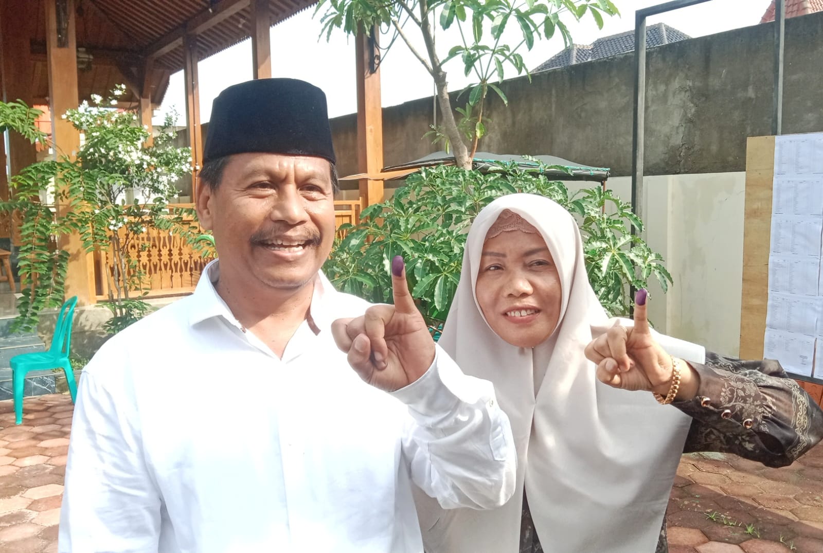 RAMPUNG NYOBLOS: Harno bersama istri menunjukkan tinta di jari kelingking setelah menyalurkan hak lilih di TPS 4, Desa Sidowayah pada Rabu (27/11). (VACHRI RINALDY L/RADAR KUDUS)