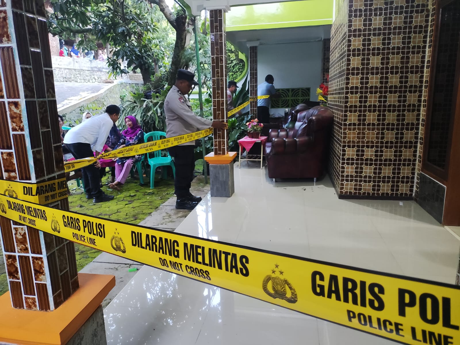 MASIH TANDA TANYA: Polisi memasang garis polisi di rumah pasangan suami istri yang tewas di rumahnya di Desa Ternadi, Dawe, Kudus. (GALIH ERLAMBANG W/RADAR PATI)
