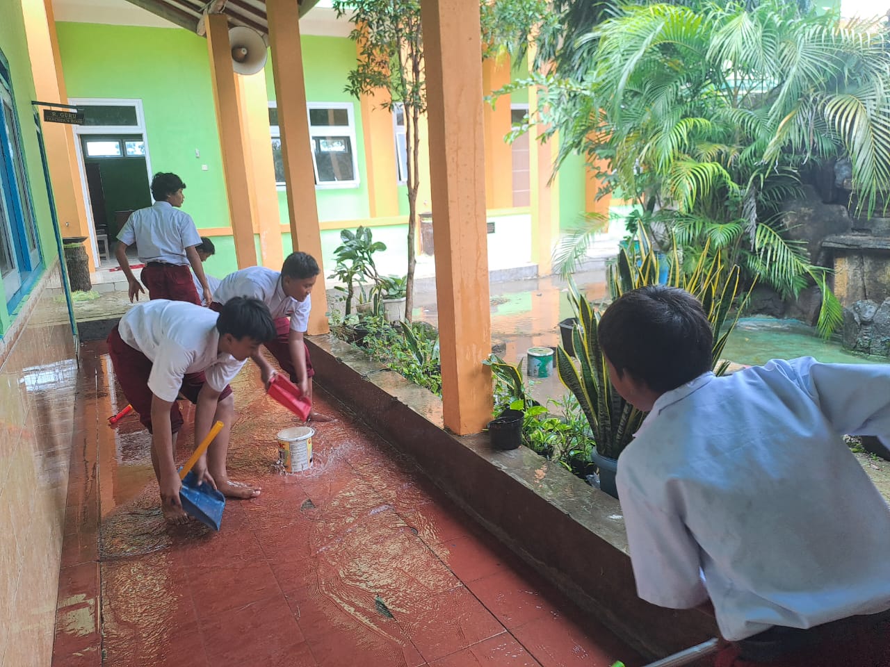 Anak-anak di SD Negeri Poncomulyo sedang membersihkan teras sekolah usai terendam banjir kemarin.