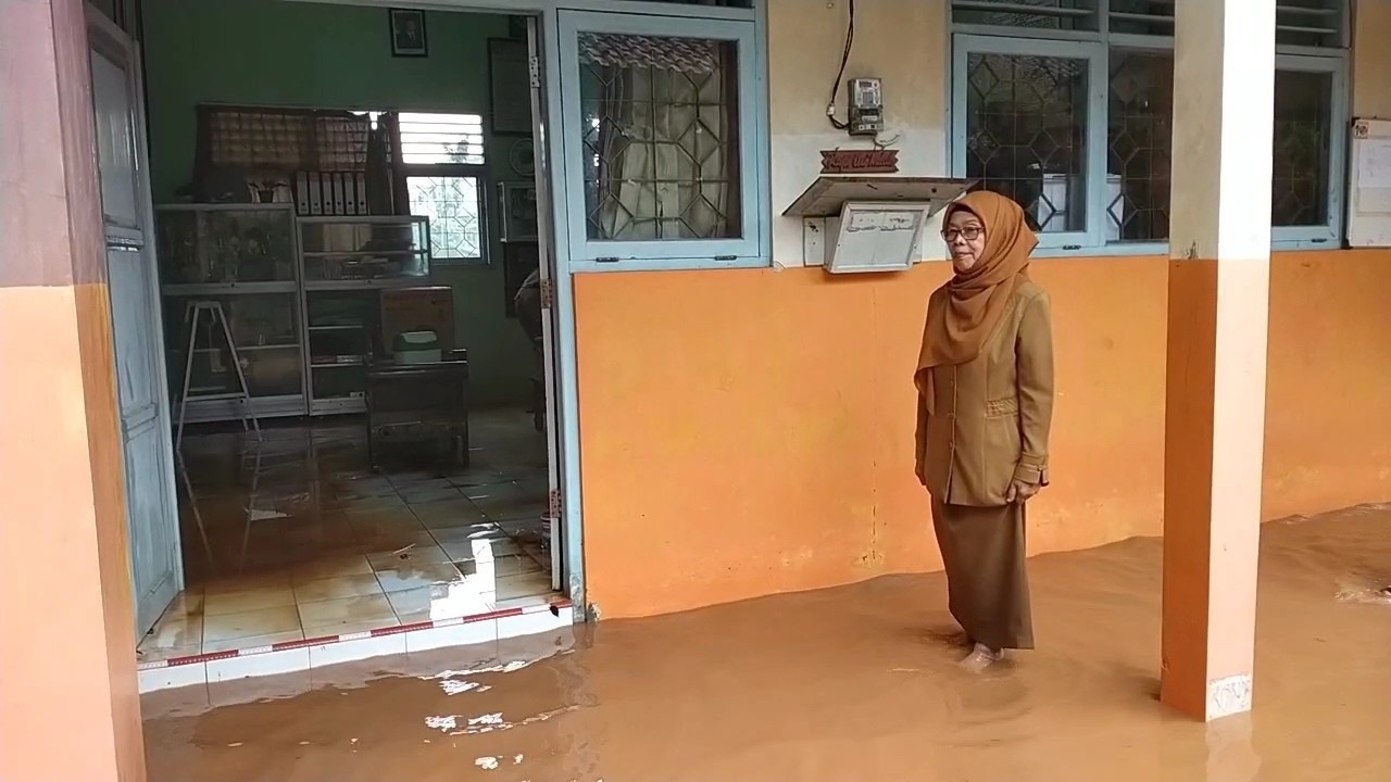 KEBANJIRAN: Guru SLB Pati mengecek kondisi banjir di lingkungan sekolah kemarin.