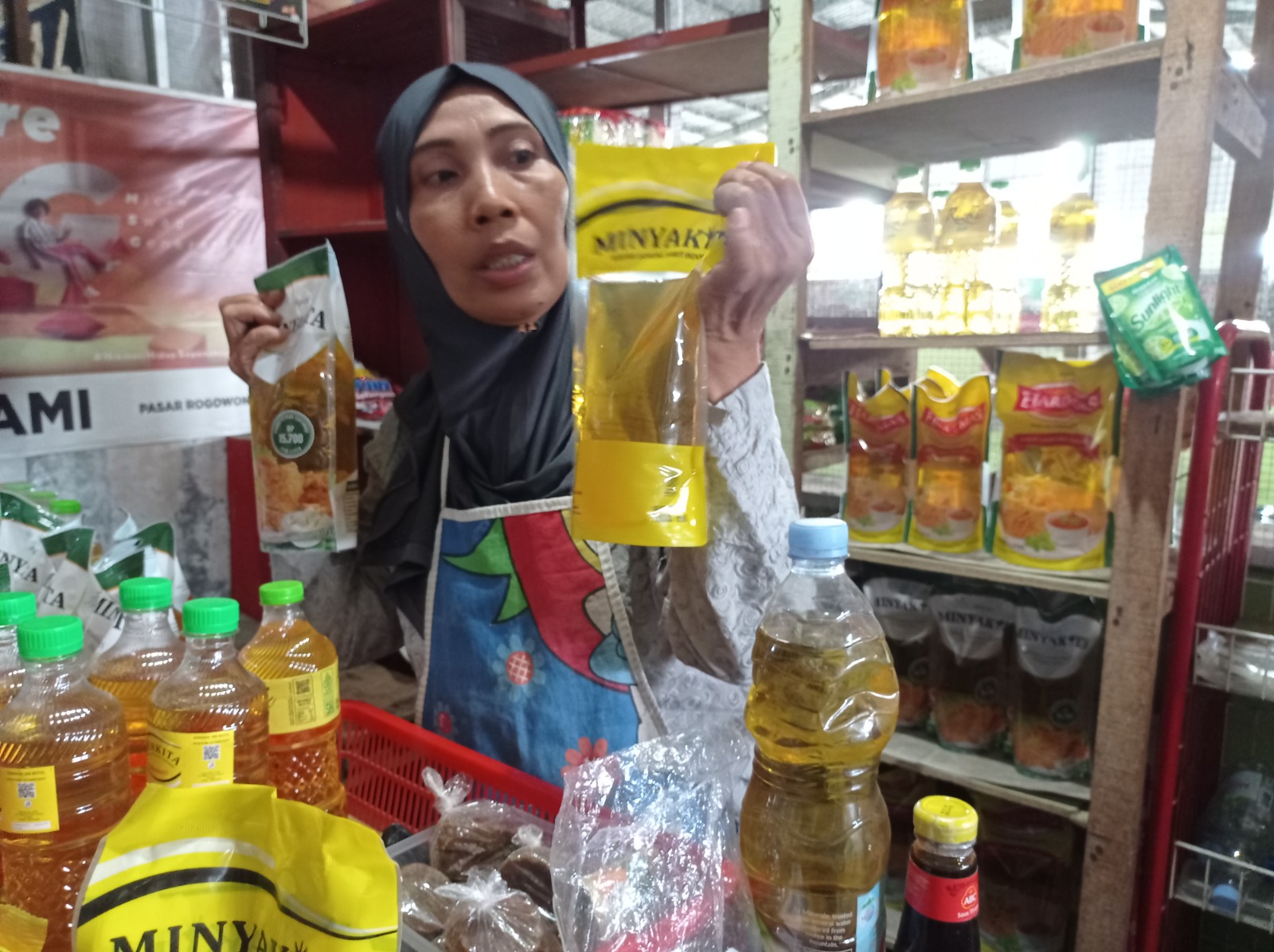 Salah seorang pedagang sembako di Pasar Rogowongso menunjukkan salah satu produk Minyakita yang dikomplain pembeli, Selasa (11/3). (ACHMAD ULIL ALBAB/RADAR KUDUS)