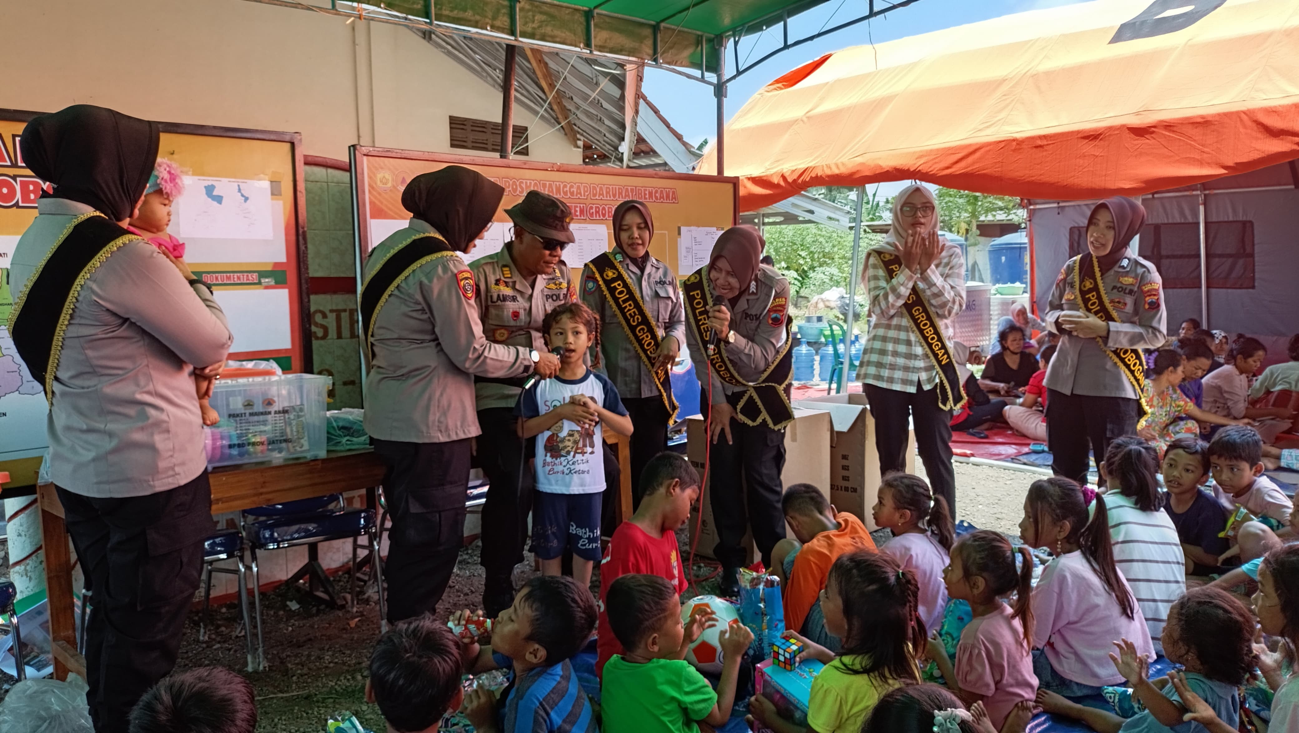BERIKAN HIBURAN &mdash; Anggota Polres Grobogan memberikan hiburan kepada anak yang berada di tempat pengungsian di Desa Ringin Kidul yang terkena musibah banjir. (POLRES GROBOGAN FOR RADARPATI.ID)