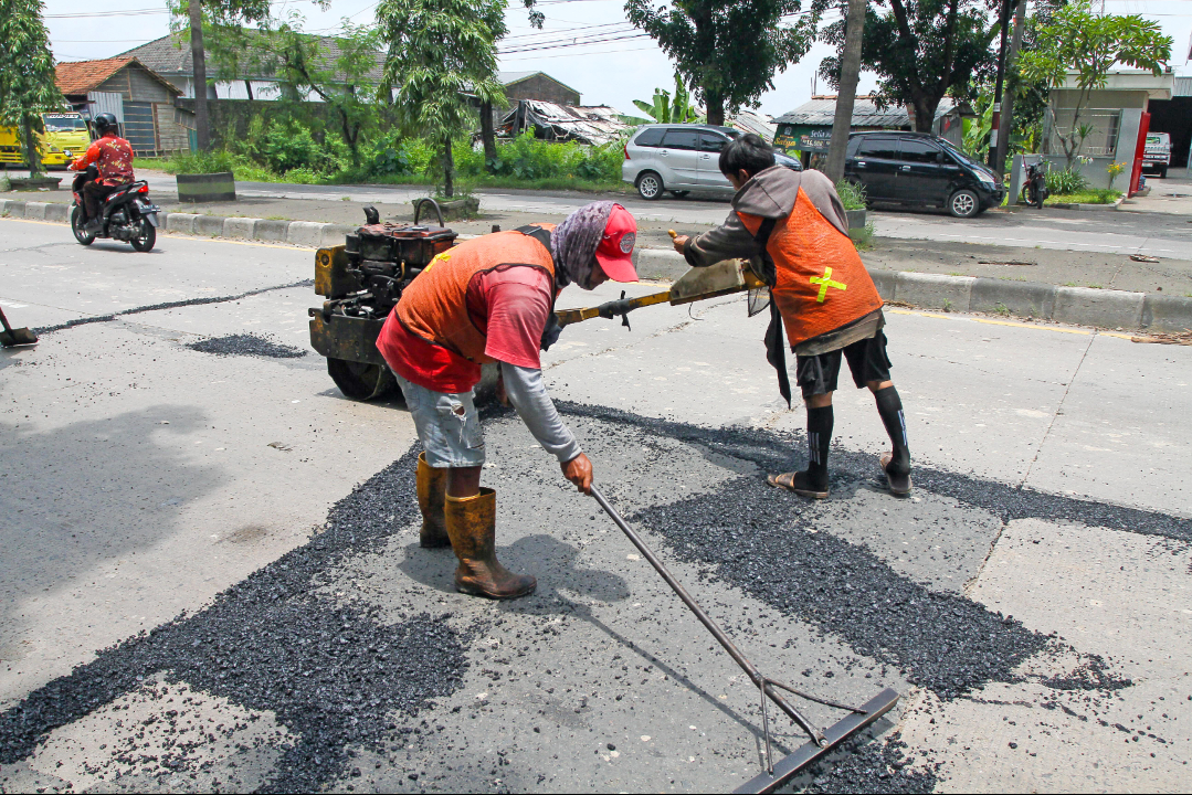 GERAK CEPAT: Pekerja menambal jalan yang berlubang di ruas Jalan Lingkar Timur kemarin. (GALIH ERLAMBANG W/ RADARPATI.ID)
