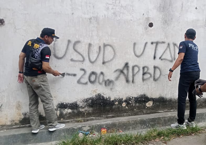 BERSIHKAN TULISAN: Para petugas Satpol PP Rembang membersihkan aksi vandalisme bertulis "Usut Utang 200 M APBD" kemarin.