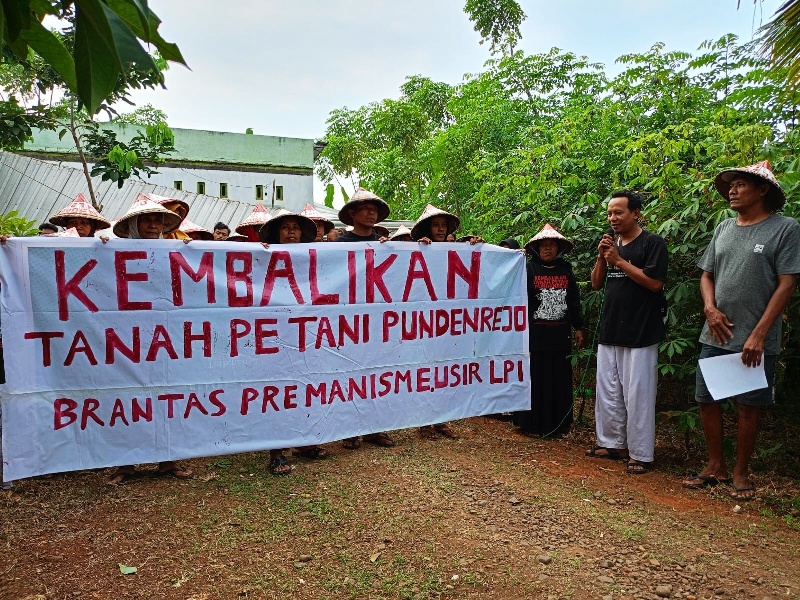 BERDIRI: Petani Pundenrejo, Tayu memegang spanduk di lahan sengketa belum lama ini.