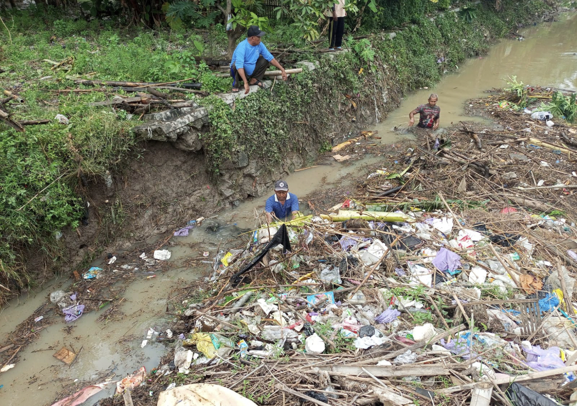 KERJA BAKTI: Warga membantu kerja bakti urai sampah yang tersumbat, satu sisi stakeholder terkait mengecek kondisi di Trahan dari atas jembatan, Selasa lalu (17/6). BPBD RBG UNTUK RADARPATI.ID