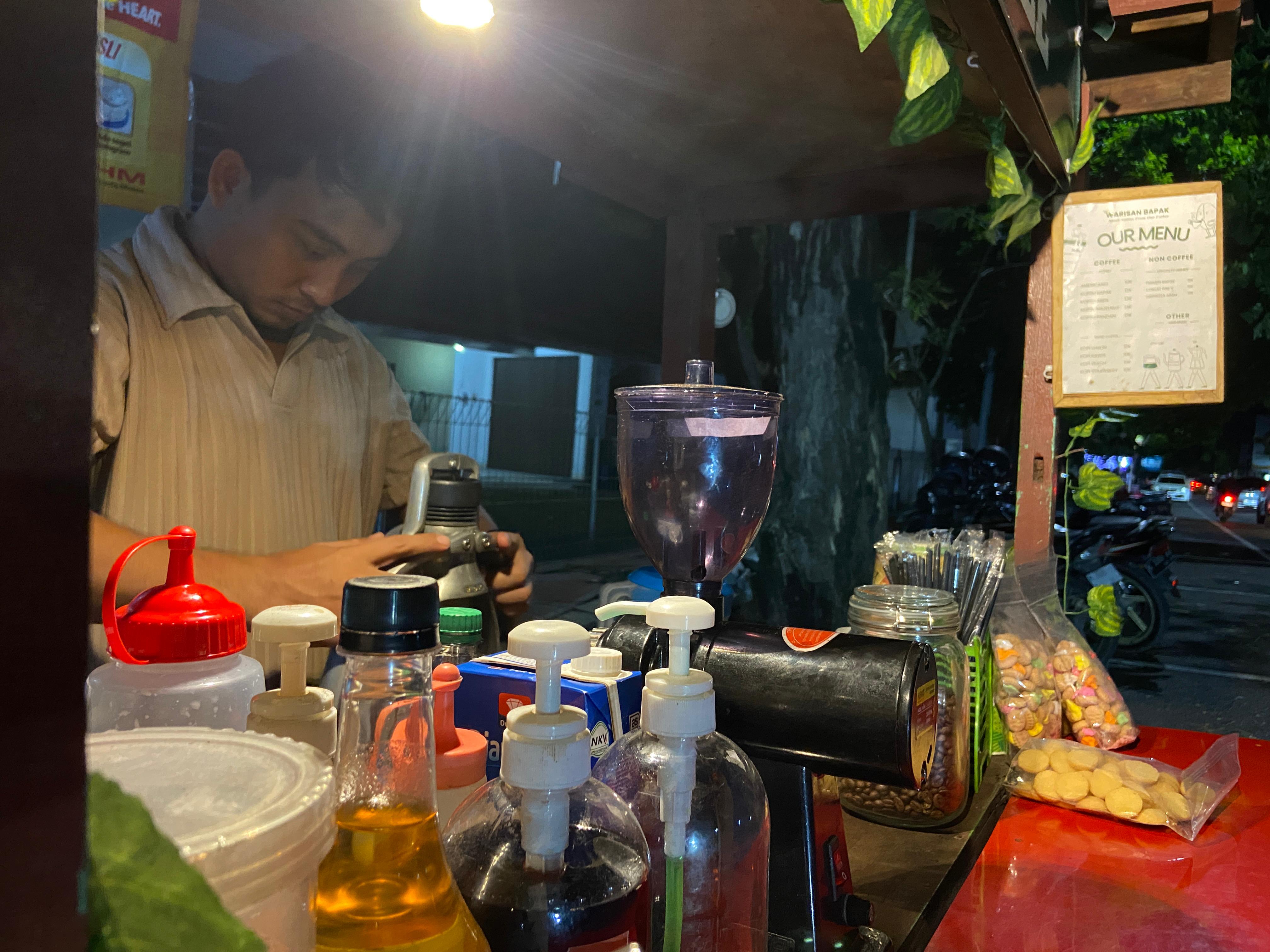 BIKIN KOPI: Proses pembuatan kopi oleh penjual kopi, Nur Ahmad Qomarudin, di depan pembeli yang sedang duduk berbincang, kemarin.