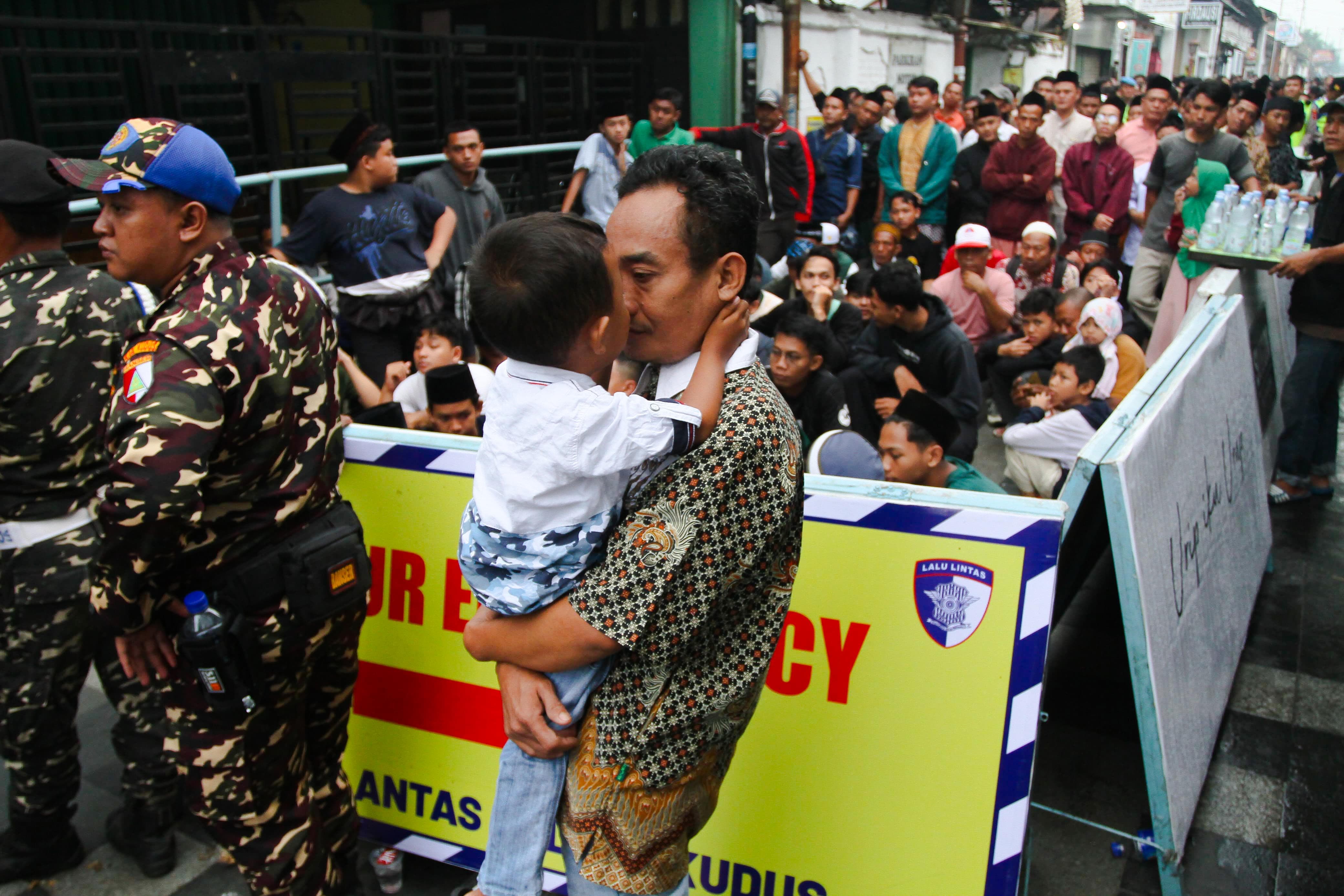 RELA ANTRE: Seorang warga menggendong anaknya untuk antre mendepatkan Nasi Jangkrik pada tradisi Buka Luwur Makam Sunan Kudus Minggu (6/7)