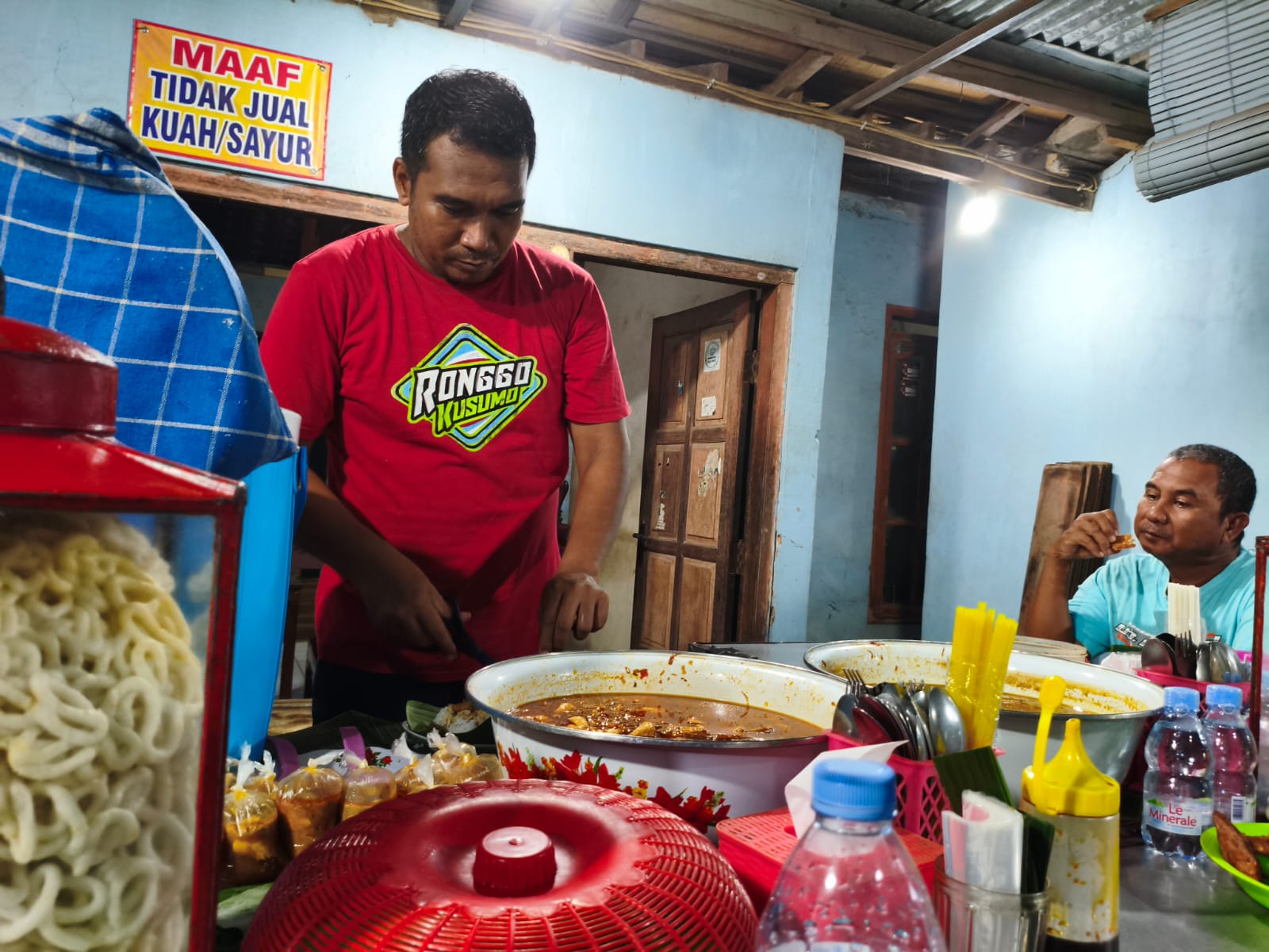 Alip menyajikan sepiring nasi tahu di warungnya kepada pelanggan.