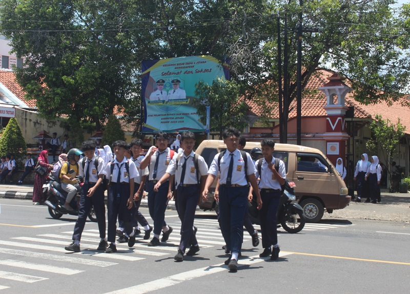 MENYEBERANG: Sejumlah siswa-siswi SMPN 5 Jepara telah pulang sekolah dan menunggu jemputan masing-masing.