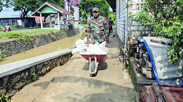 USUNG MATERIAL: TNI-Polri bersama warga menambal tanggul jebol di Desa Ketitang Wetan, Batangan kemarin.(ANDRE FAIDHIL FALAH)