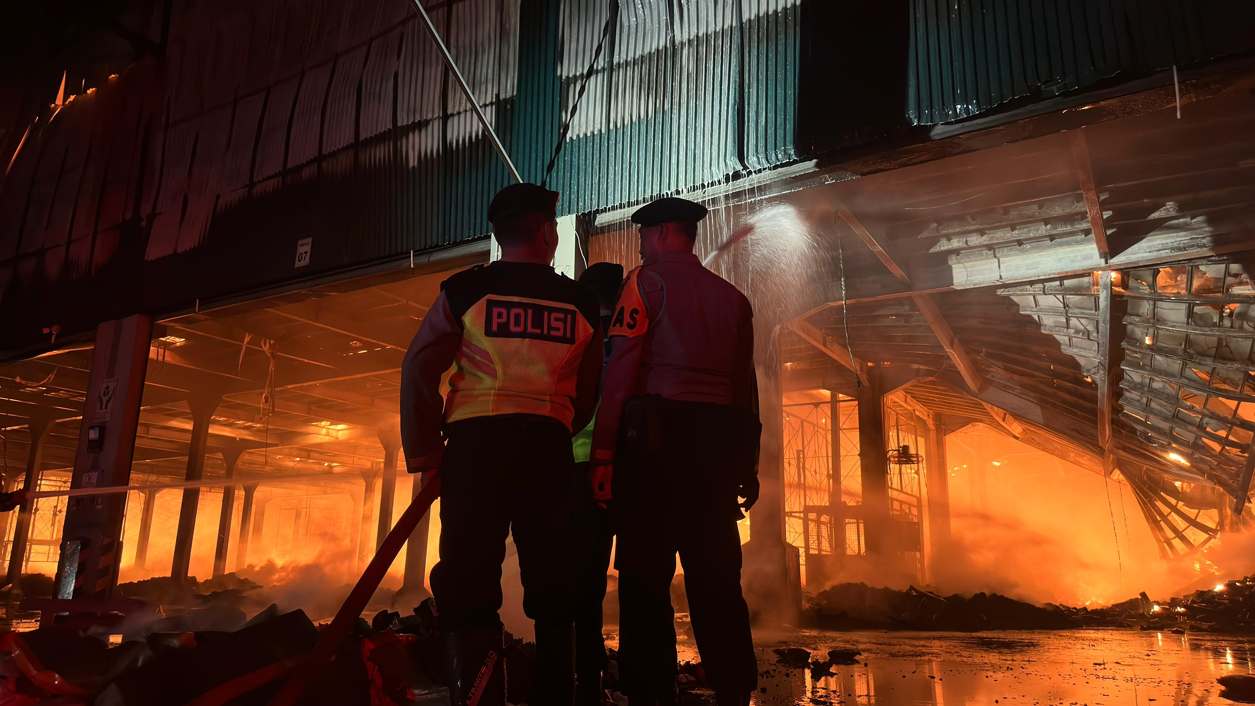 KESULITAN: Personel Polresta Pati membantu pemadaman kebakaran gudang PT Dua Kelinci Pati hingga dini hari (2/12/2025).