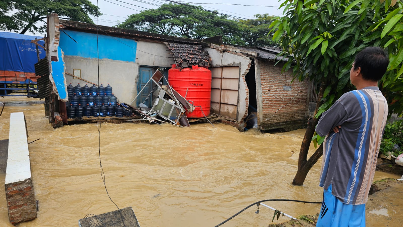 Warga melihat sebuah bangunan ruko di tepi Jalan Pantura Batangan Pati yang hanyut akibat banjir. (WARGA UNTUK RADAR PATI)