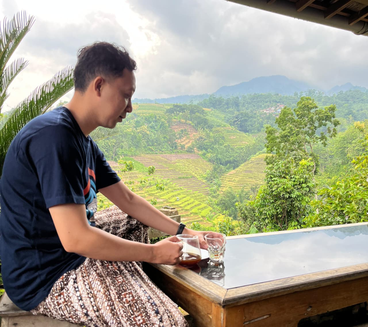 Seorang pelanggan setia sedang menikmati kopi sambil melihat pemandangan kaki Gunung Muria.